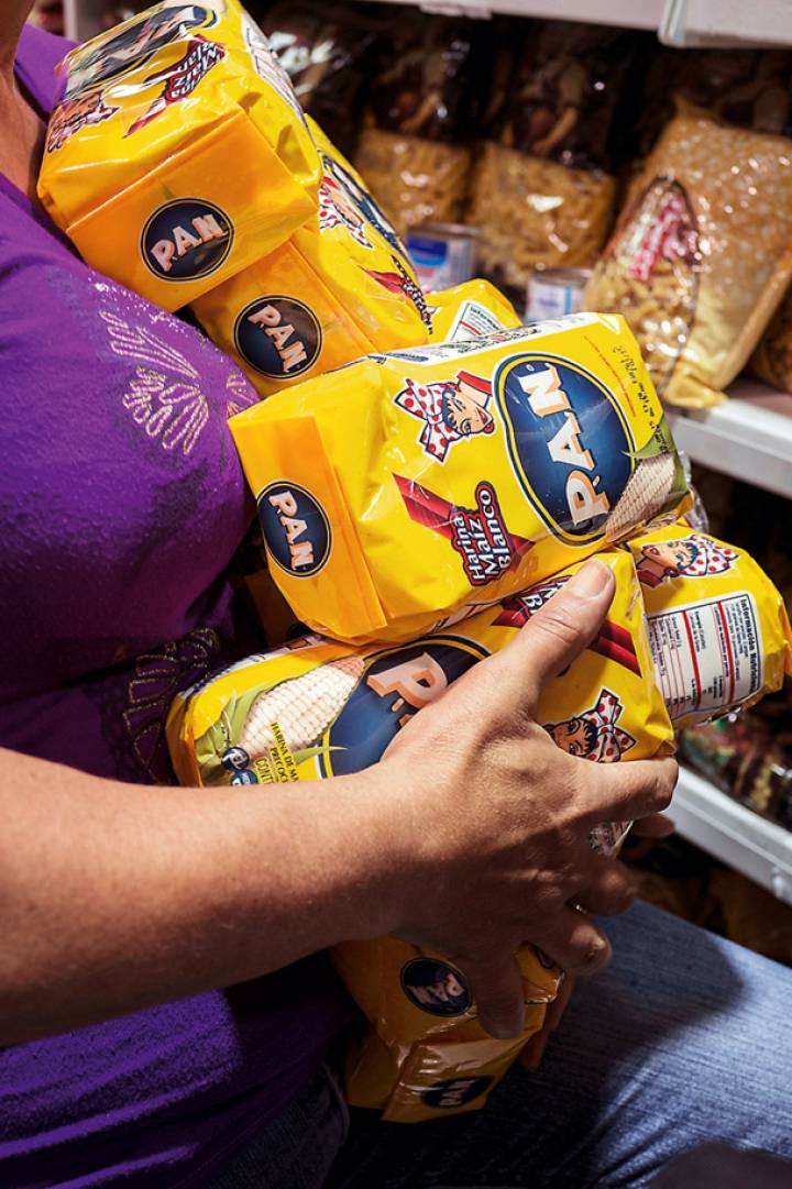 Mulher carrega pacotes de farinha para arepas, um dos produtos básicos em falta. Mulher carrega pacotes de farinha para arepas, um dos produtos básicos em falta.