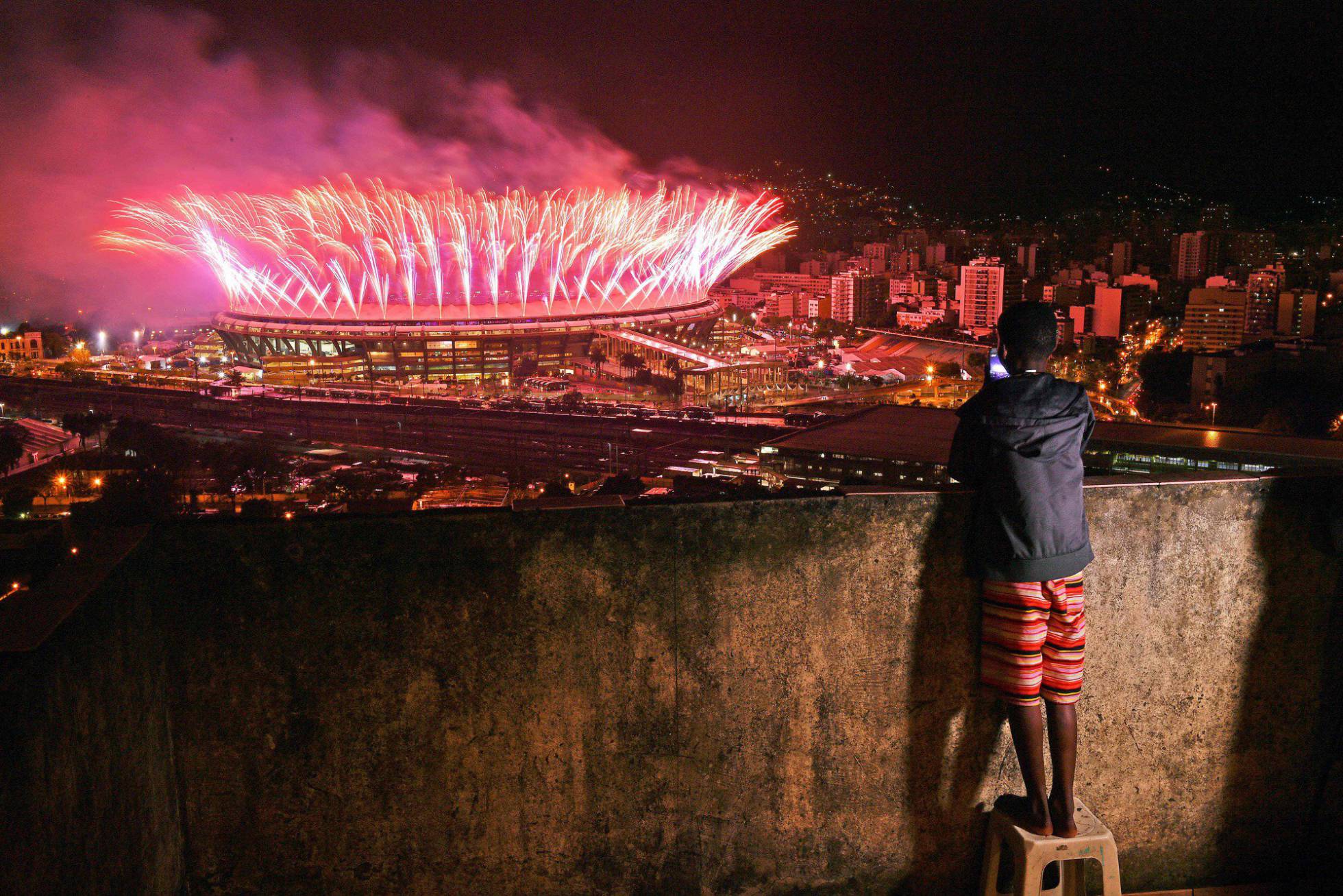 Menino assiste da comunidade da Mangueira a queima de fogos da cerimônia de encerramento da Olimpíada no Maracanã. Menino assiste da comunidade da Mangueira a queima de fogos da cerimônia de encerramento da Olimpíada no Maracanã.