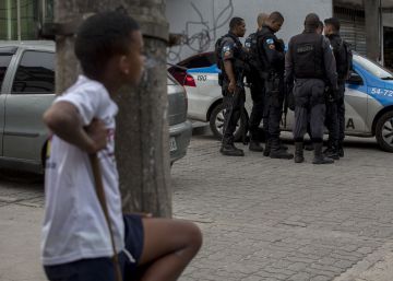 Uma crian&ccedil;a observa um grupo de policiais na Cidade de Deus, no Rio.
