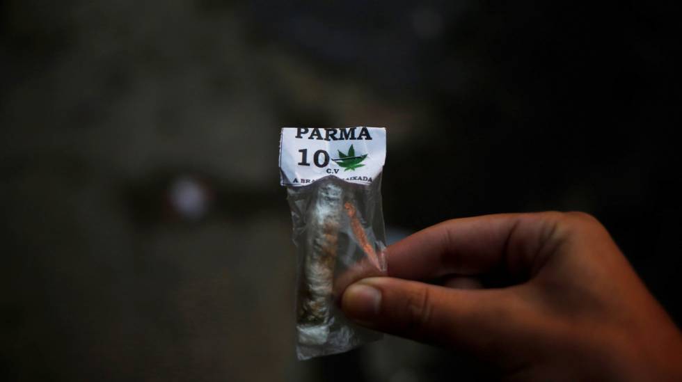Homem mostra um pacote com maconha com a marca do Comando Vermelho, no Rio de Janeiro, em junho de 2016.