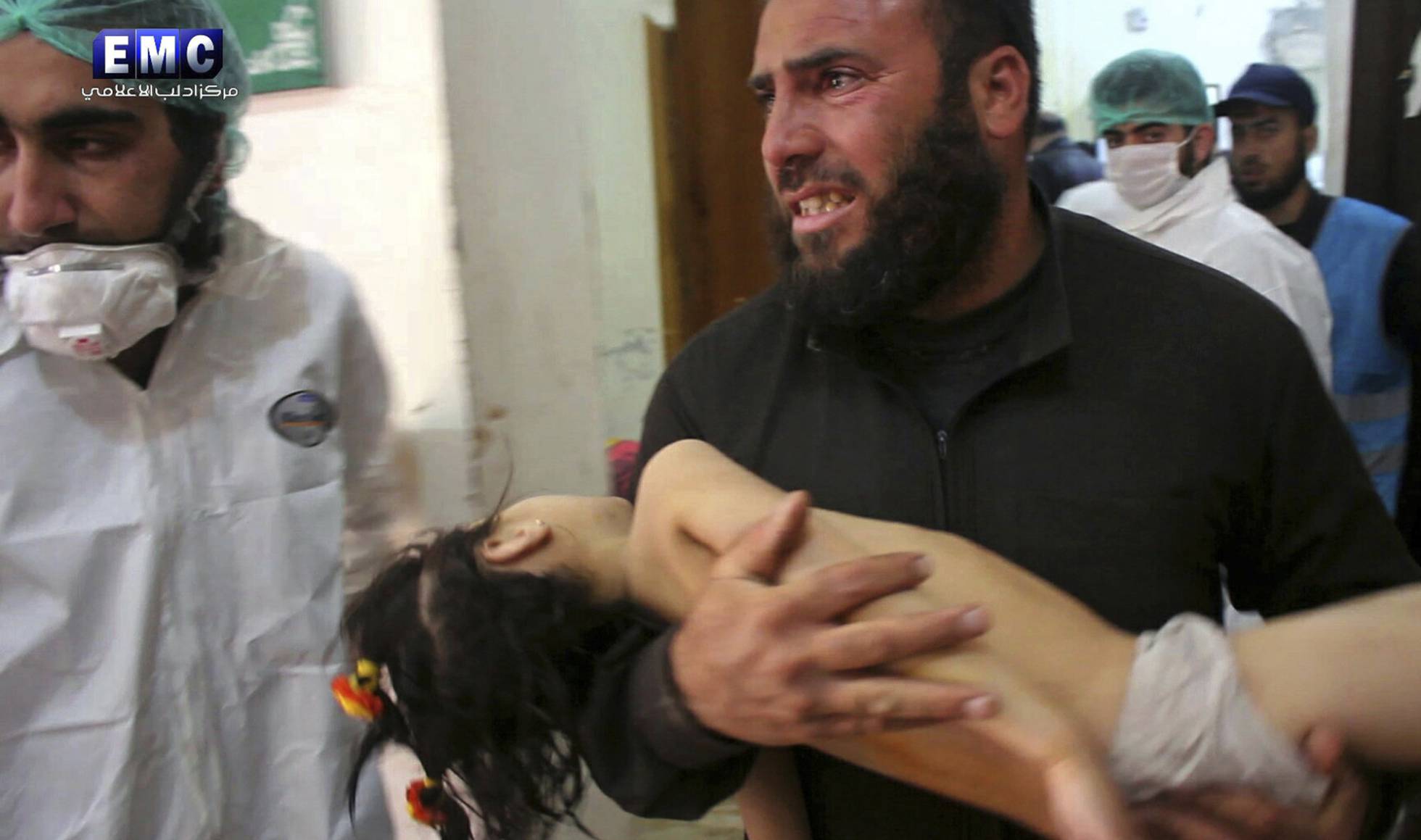 Homem leva menina nos braços ao pronto-socorro na localidade atacada com armas químicas.