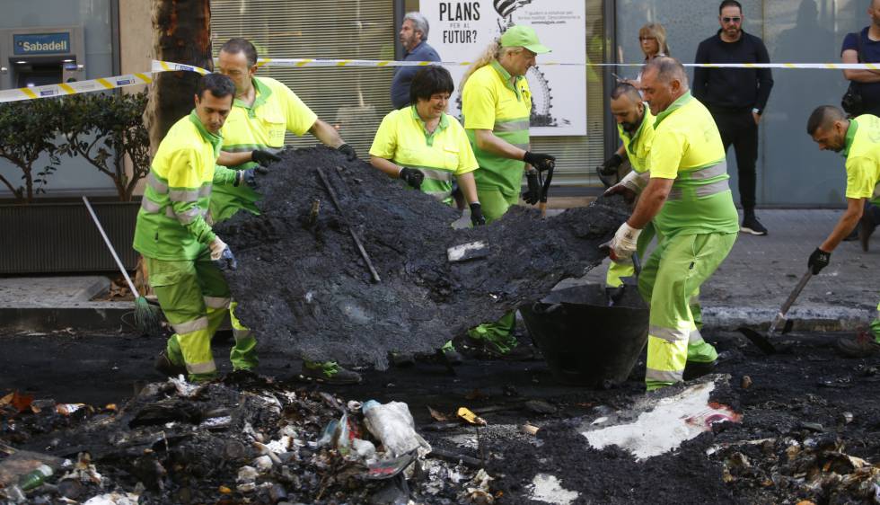 Operaris retiren les restes de contenidors cremats.