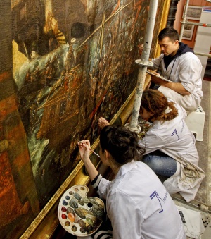 Tres restauradores trabajan en el lienzo.
