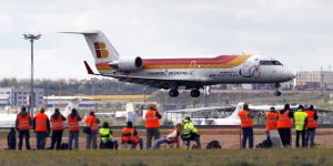 Un grupo de personas dirige su objetivo hacia un aeroplano que está aterrizando.