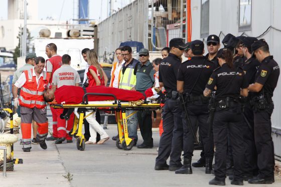 Uno de los náufragos es evacuado en camilla a la llegada al puerto de Alicante.