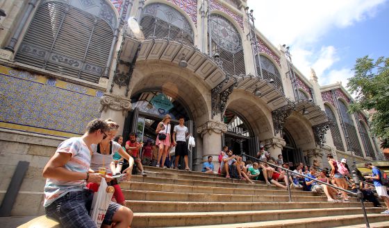 Turistas descansan en la escalinata de entrada al Mercat Central de Valencia.