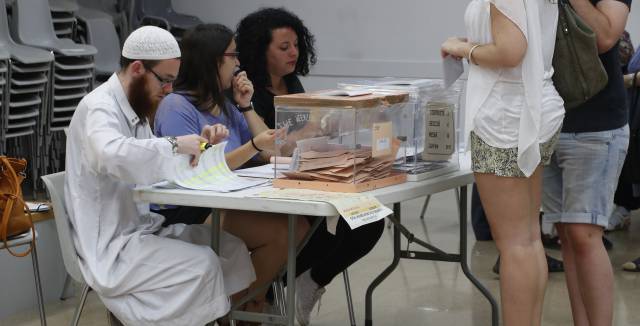 David Franco Portolés checks ID cards at a polling station. David Franco Portolés checks ID cards at a polling station.