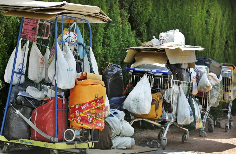 Una persona sin techo duerme junto a unos jardines de Valencia y sus pertenencias.