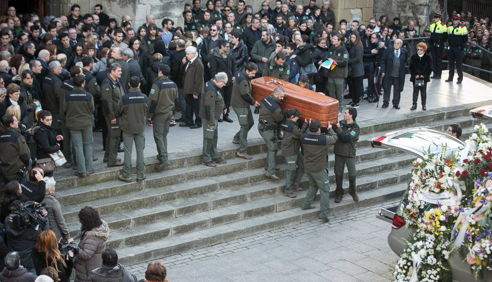 Compañeros de los agentes trasladan el féretro de una de las víctimas en su funeral.