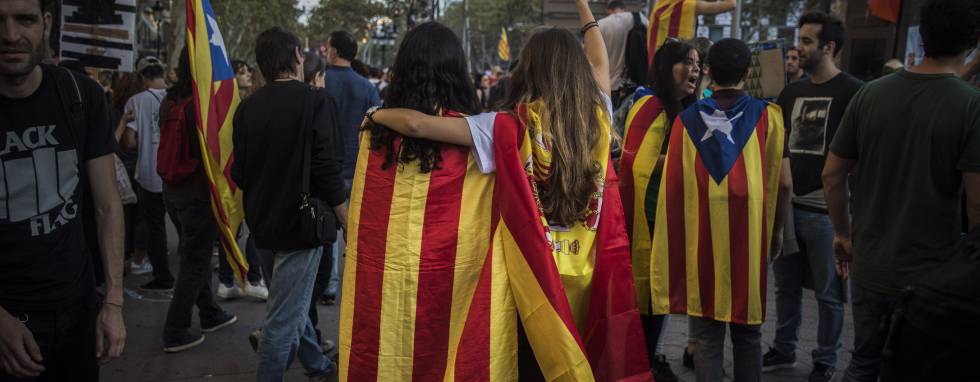 Two girls, one with a Catalan independence flag wrapped on her shoulders walks together with another one with a Spanish flag as demonstrators gather in downtown Barcelona, Spain, Tuesday Oct. 3, 2017. Thousands of people are demonstrated in Barcelona in protest at what they say was police brutality during a referendum on Catalonia's secession from Spain that was previously declared illegal by Spain's Constitutional Court.(AP PhotoSanti Palacios)