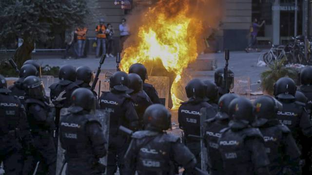 Antidisturbios de la Policia Nacional delante de un gran fuego en Via Laietana, en Barcelona.