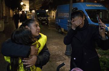Gabriela García abraza a Sofía, mientras su madre, Paola Pérez, hace una videollamada con su marido que sigue en Colombia. Ella y sus tres hijos pasaron una noche frente al Samur.