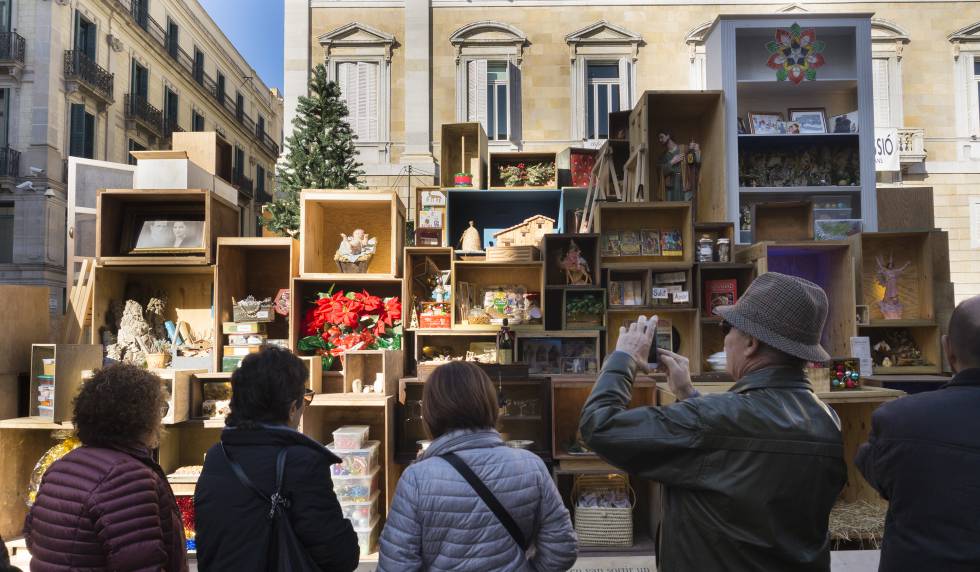 Diverses persones fotografien el pessebre de plaça Sant Jaume de Barcelona.