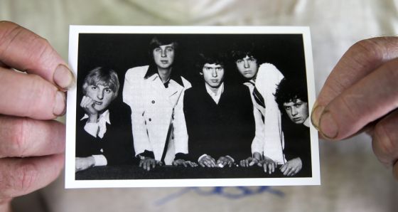 Chris Stewart sujeta una foto de la primera formación de Genesis, en la que él aparece a la derecha.