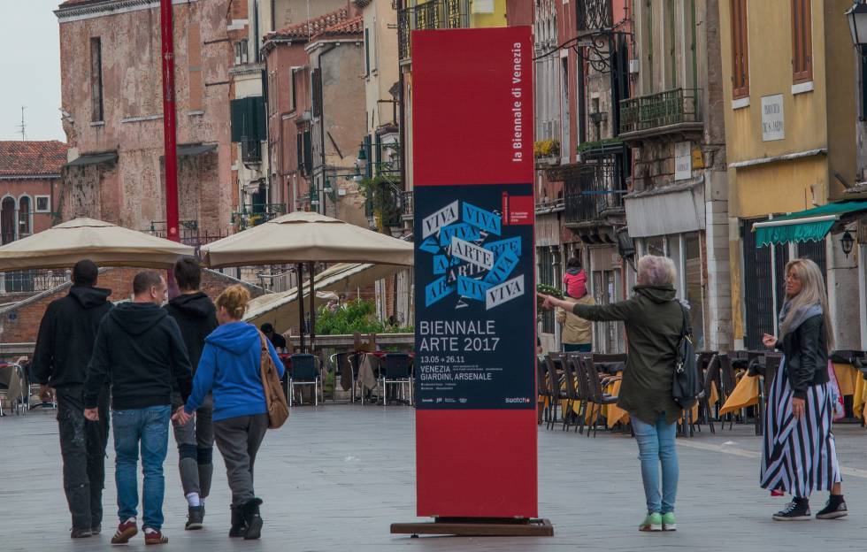 Turistas observan ayer lunes un cartel que anuncia la 57ª Bienal de Venecia.