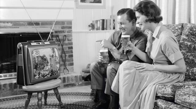Una pareja mira su televisión portátil en una fotografía tomada en los años sesenta.