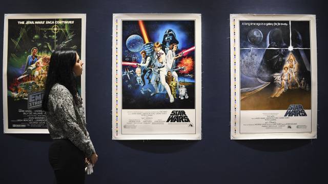 Una empleada de Sothebys observa unos carteles originales de las primeras películas de Star Wars que pondrá a subasta.