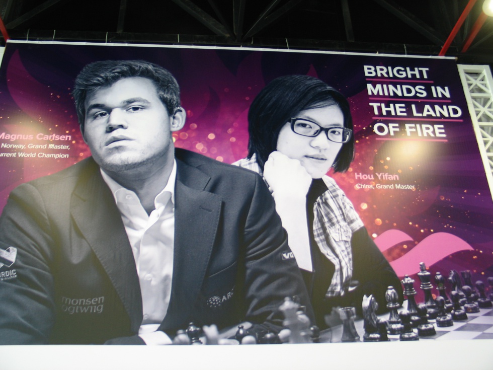 Cartel anunciador de la Olimpiada con los campeones del mundo, Magnus Carlsen y Yifán Hou, y el lema