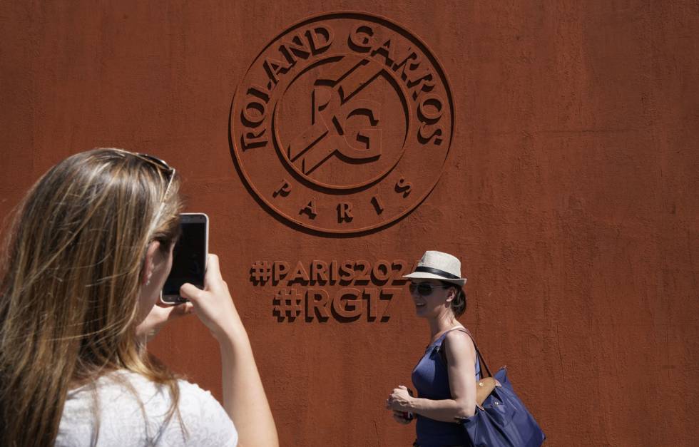 Dos aficionadas posan delante de un mural de Roland Garros.
