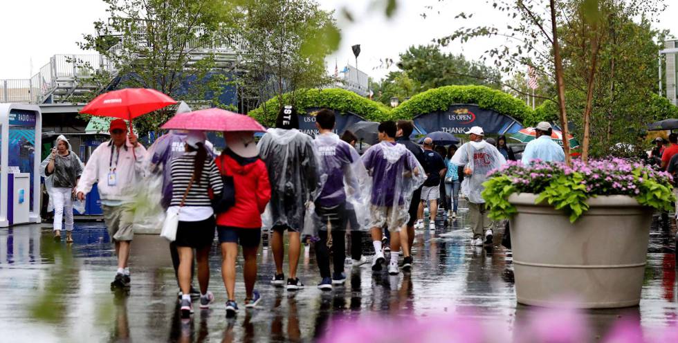 Asistentes se protegen de la lluvia en el complejo Billie Jean King.