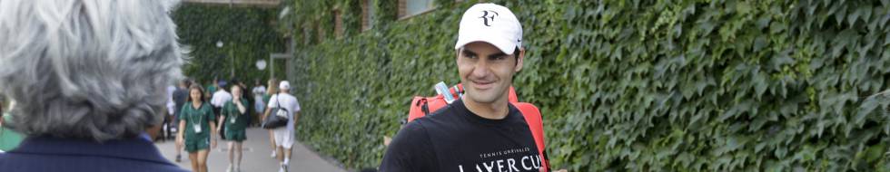 Federer saluda a un aficionado en Wimbledon.
