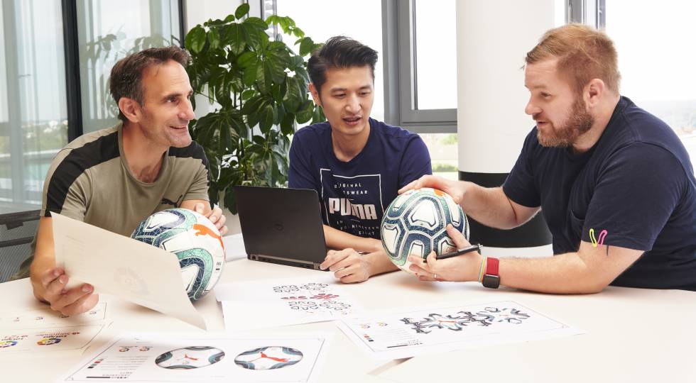 Thomas Schwarz (izquierda), jefe de Producto Deportivo de PUMA, con su compañero Tom Lin y Carl Tuffley (derecha), jefe de diseño, con los primeros ejemplares del balón de LaLigay sus bocetos.