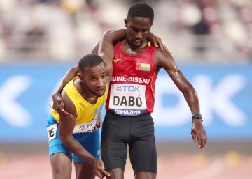 Jonathan Busby, de Aruba, completa los 5.000 metros ayudado por otro atleta
