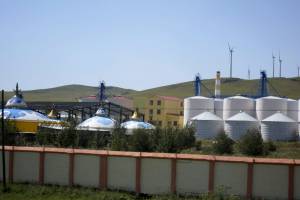 Imagen de unos silos de grano junto a las construcciones típicas de la Mongolia Interior (China) con molinos de viento en el distrito de Hulunber, conocido como