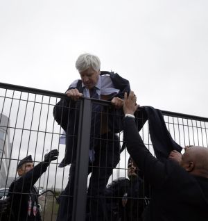 Pierre Plissonnier, con el traje y la camisa rasgados, trata de saltar una valla con ayuda de los agentes de seguridad después de que cientos de trabajadores tomasen la sede de Air France por el plan de ajuste.