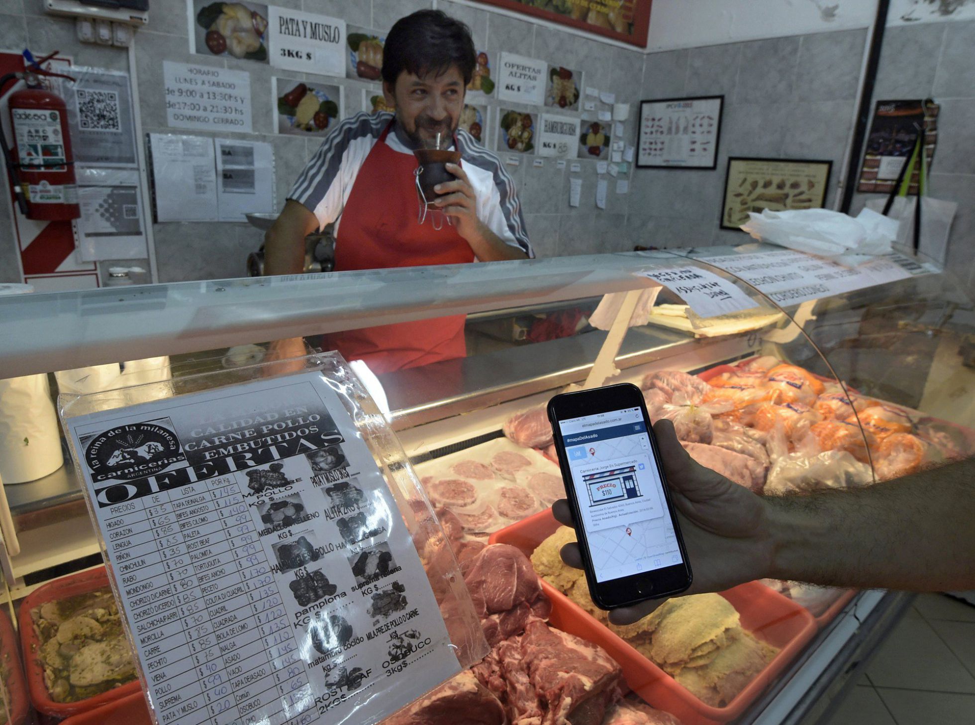 Un cliente comprueba con su móvil los precios de una canicería. Un cliente comprueba con su móvil los precios de una canicería.