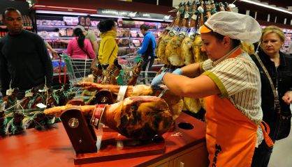 Una empleada cortando jamón en un supermercado.