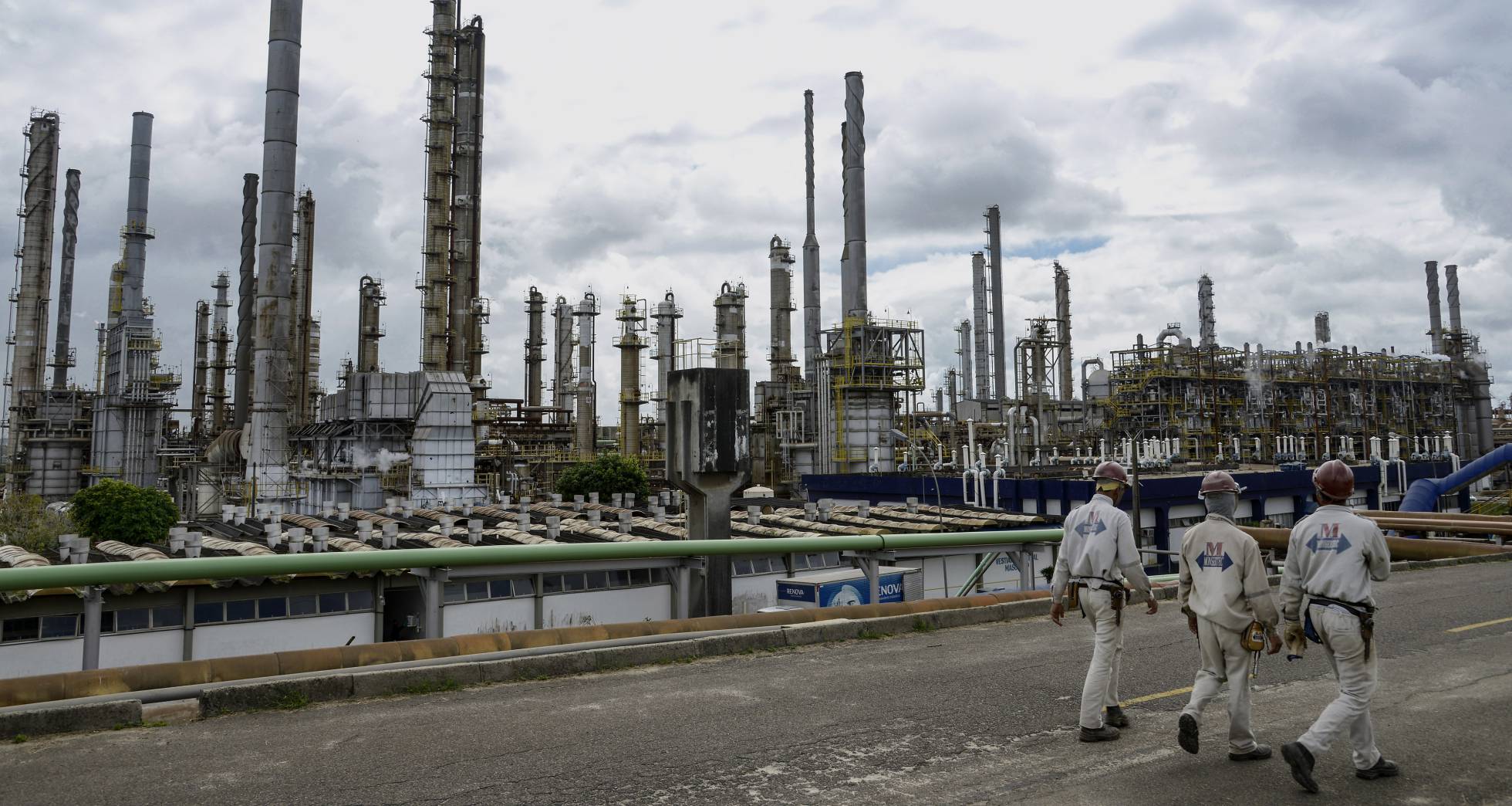 Trabalhadores passeiam diante da indústria petroquímica em Camaçari, no Brasil Trabalhadores passeiam diante da indústria petroquímica em Camaçari, no Brasil