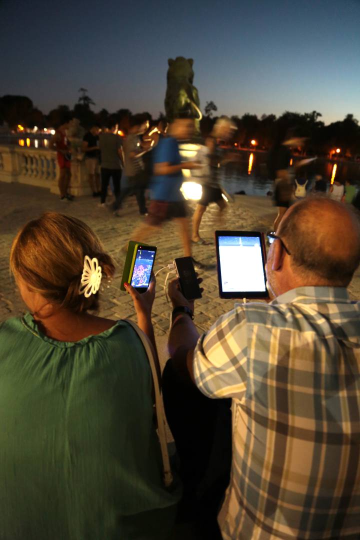 Dos personas juegan a Pokémon Go con sus dispositivos conectados a una única batería portátil. Dos personas juegan a Pokémon Go con sus dispositivos conectados a una única batería portátil.