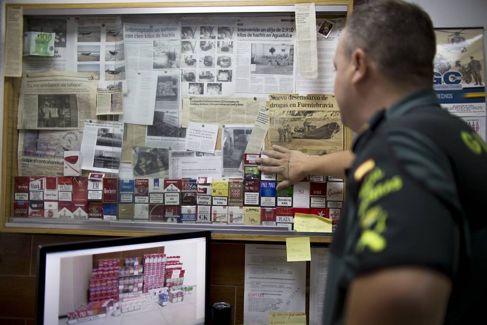 Un agente del grupo Fiscal y Fronteras de la guardia civil del Puerto de Santa María en Cádiz, junto a varias muestras de tabaco ilegal incautado y noticias sobre sus operacionesrn