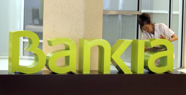 Una operaria limpia el logo de Bankia.