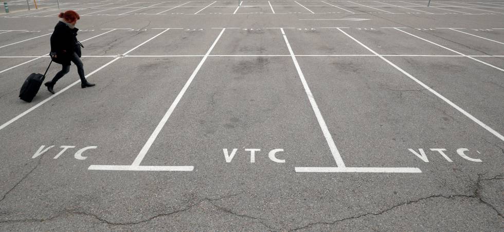 Una pasajera camina por el aparcamiento vacío de VTC en el aeropuerto de Barcelona.
