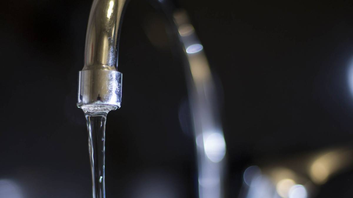 El agua mana de un grifo abierto en el fregadero de una vivienda.