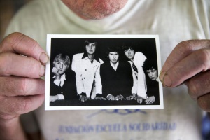 Chris Stewart holds up a photo of Genesis’s original lineup, showing him on the right.