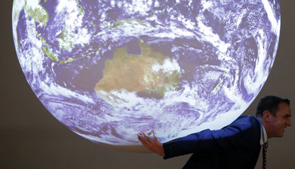 Un hombre posa con una réplica de la Tierra en la cumbre de París. Un hombre posa con una réplica de la Tierra en la cumbre de París.