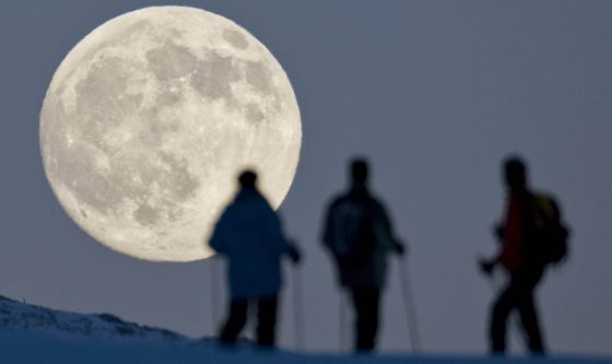 Tres practicantes del esquí de montaña contemplan la luna llena en el Weissfluhjoch, en Arosa (Suiza), el día antes del solsticio de invierno. 