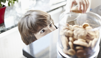 Un niño coge una galleta de un bote.