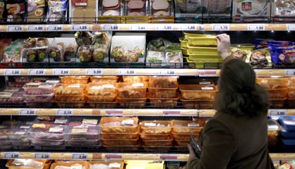 Una mujer elige productos cárnicos en un supermercado.