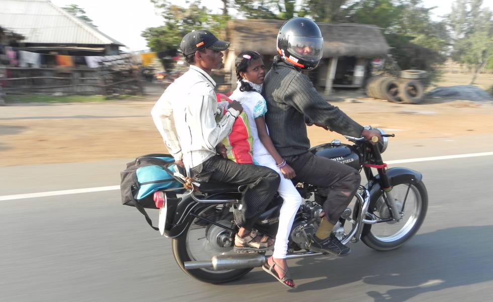 Tres personas, dos de ellas sin casco, en moto.