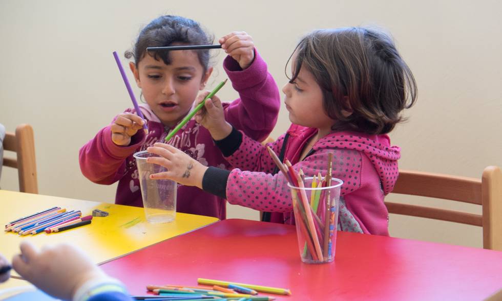 Dos niñas juegan con lápices de colores en una de las aulas.