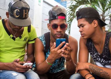 Tres jovenes conectados a internet con sus móbiles en la Habana.