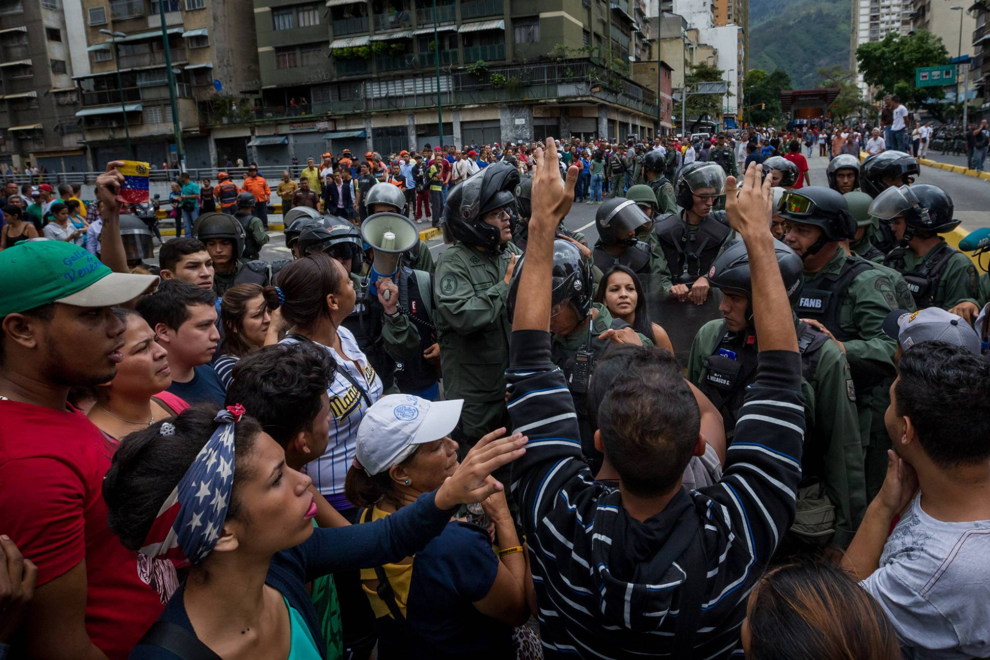 Un grupo de personas manifiestan contra miembros de la Guardia Nacional Bolivariana en Caracas en protesta por la carestía. Un grupo de personas manifiestan contra miembros de la Guardia Nacional Bolivariana en Caracas en protesta por la carestía.