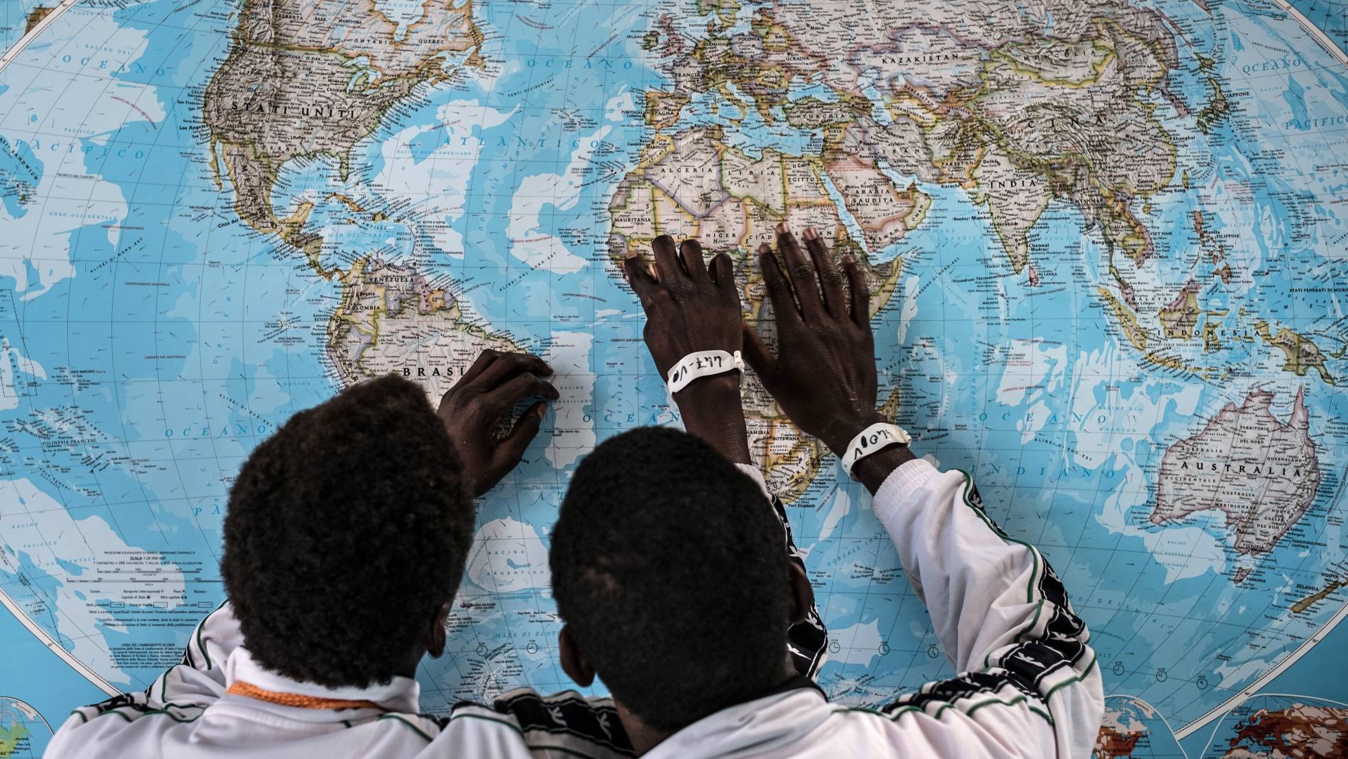 Dos menores de Gambia solicitantes de asilo en Italia, discuten sobre el viaje que han realizado en un mapa en el puerto de Pozzallo, Sicilia. Dos menores de Gambia solicitantes de asilo en Italia, discuten sobre el viaje que han realizado en un mapa en el puerto de Pozzallo, Sicilia.