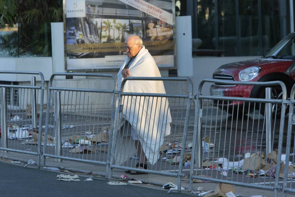 Un hombre envuelto en una colcha observa el lugar del atentado en el Paseo de los Ingleses de Niza, Francia. 