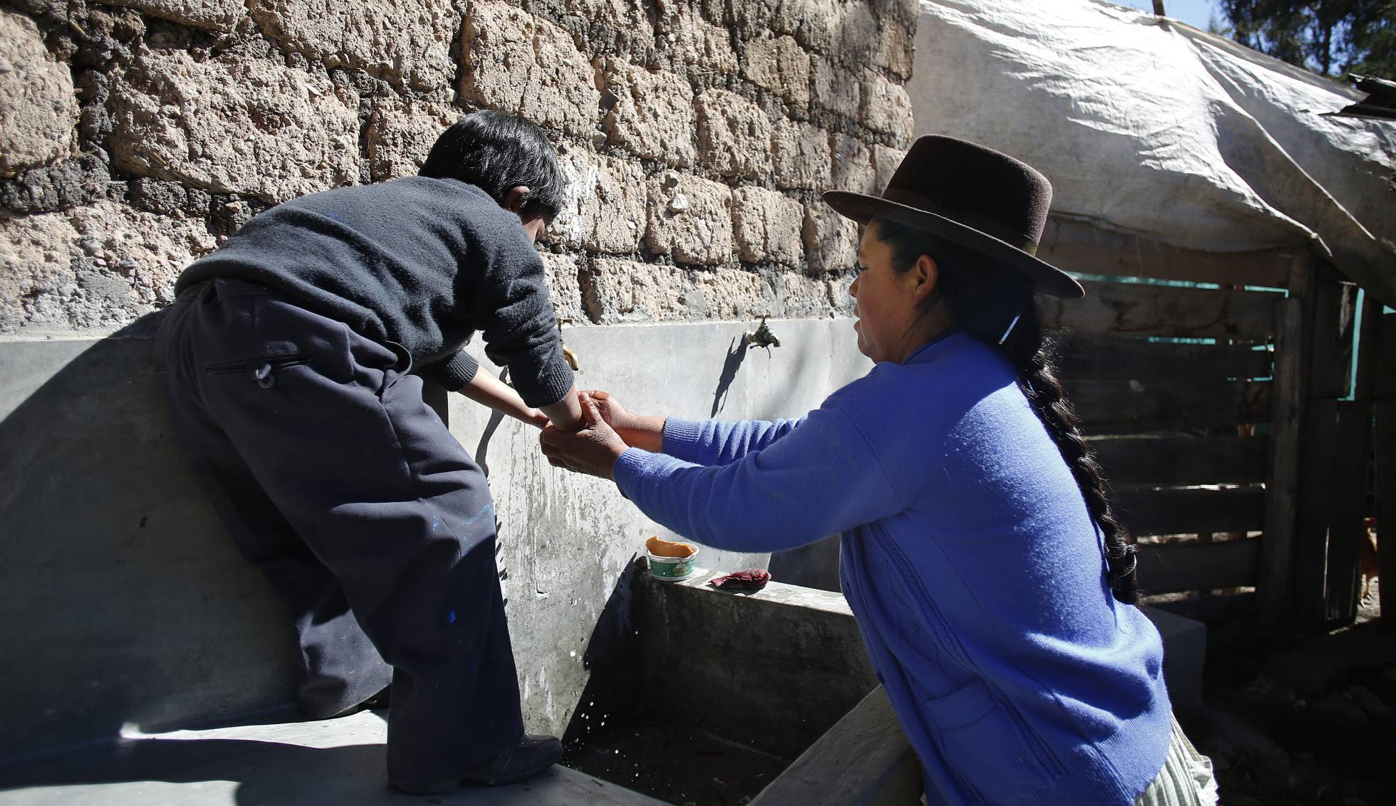 Marcelina ayuda a su hijo de seis años a lavarse las manos antes de almorzar. Marcelina ayuda a su hijo de seis años a lavarse las manos antes de almorzar.