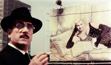 Anita Ekberg, al fondo, con un vaso de leche. En primer plano, Peppino De Filippo. La película es 'Bocaccio 70' (1962), de Federico Fellini. Anita Ekberg, al fondo, con un vaso de leche. En primer plano, Peppino De Filippo. La película es 'Bocaccio 70' (1962), de Federico Fellini.